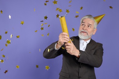 Photo of Man blowing up party popper on purple background