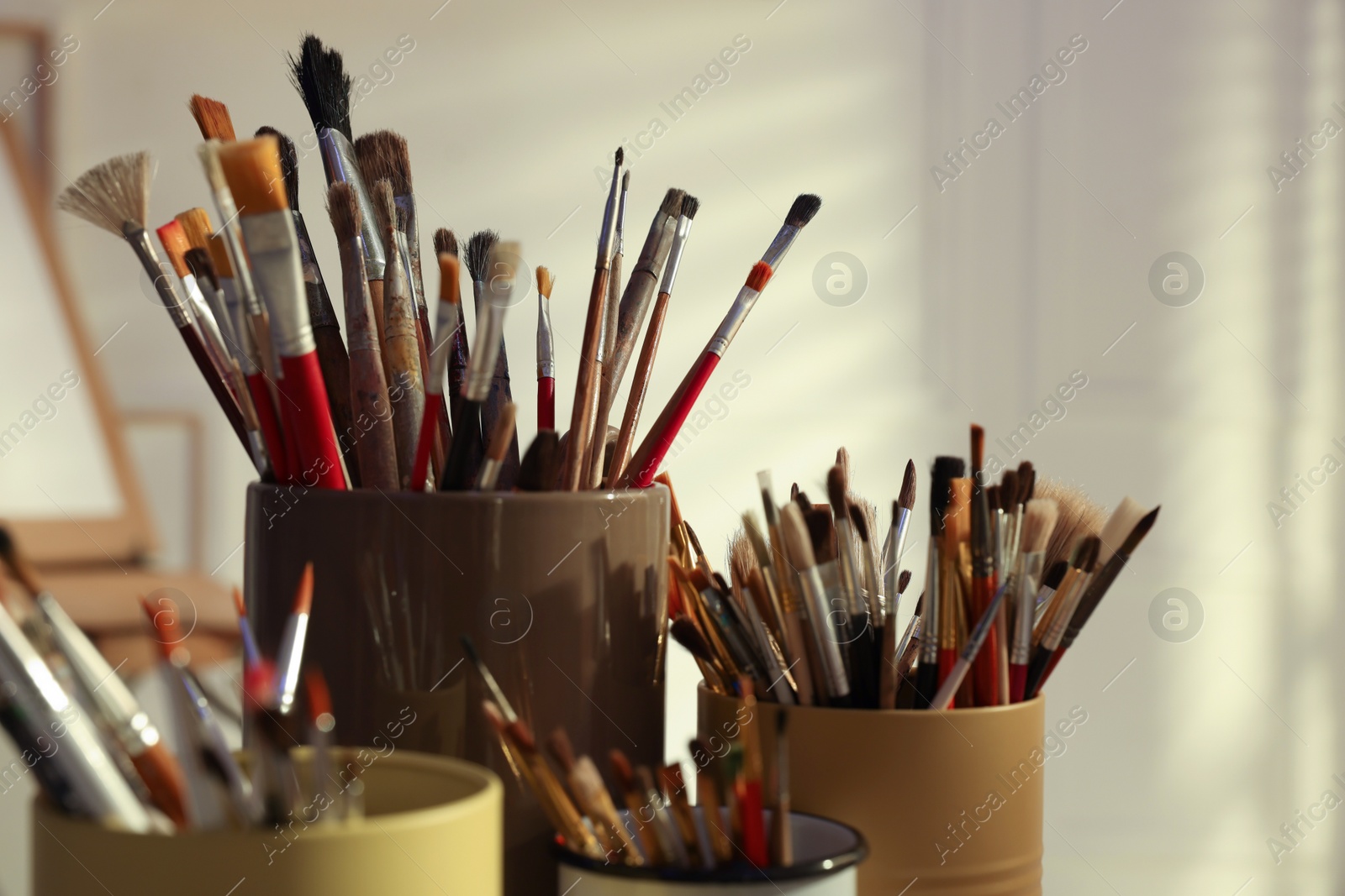 Photo of Holders with many different paintbrushes indoors, closeup
