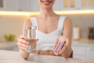 Photo of Woman with glass of water and pills at table indoors, closeup. Weight loss