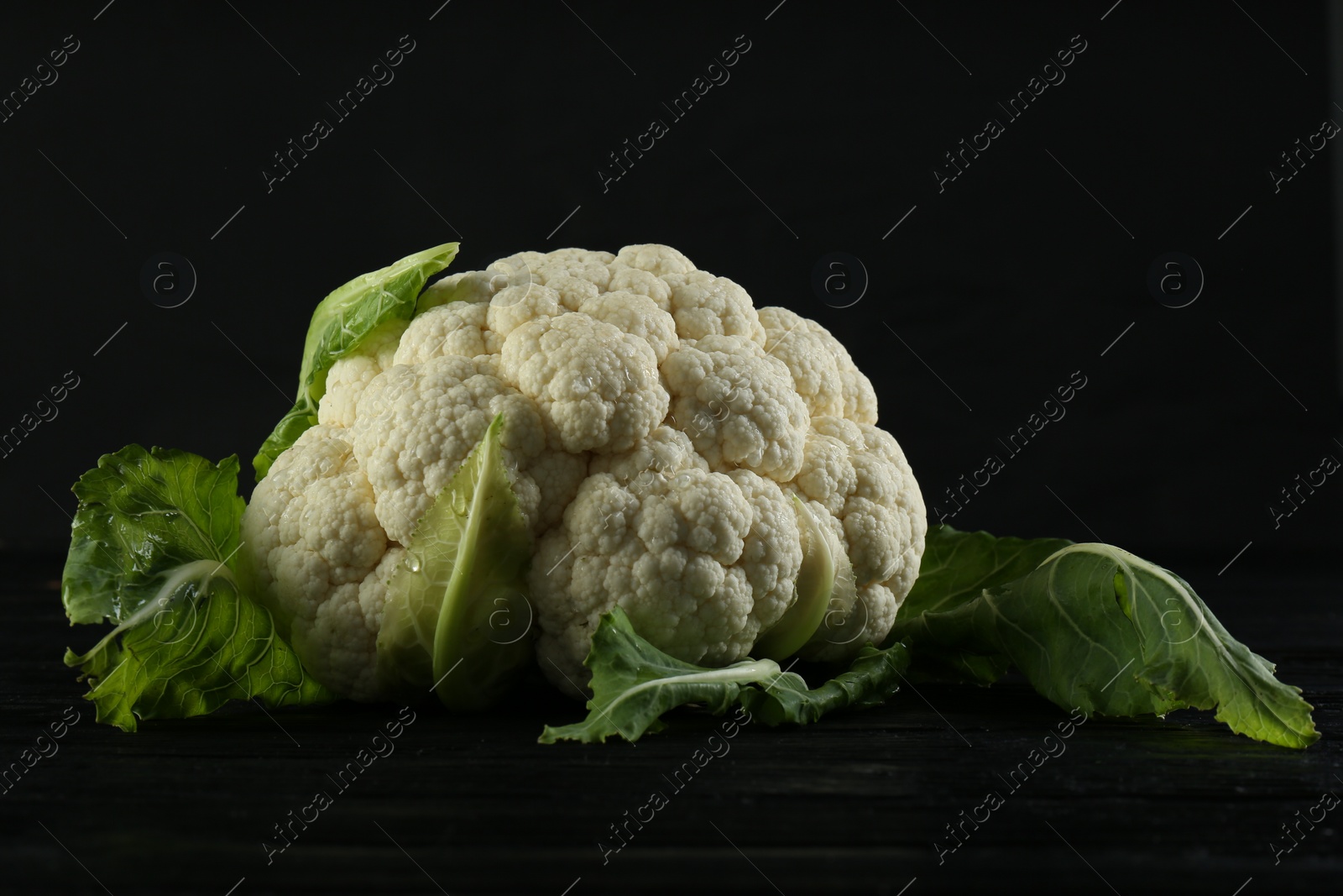 Photo of Fresh whole cauliflower on black wooden table