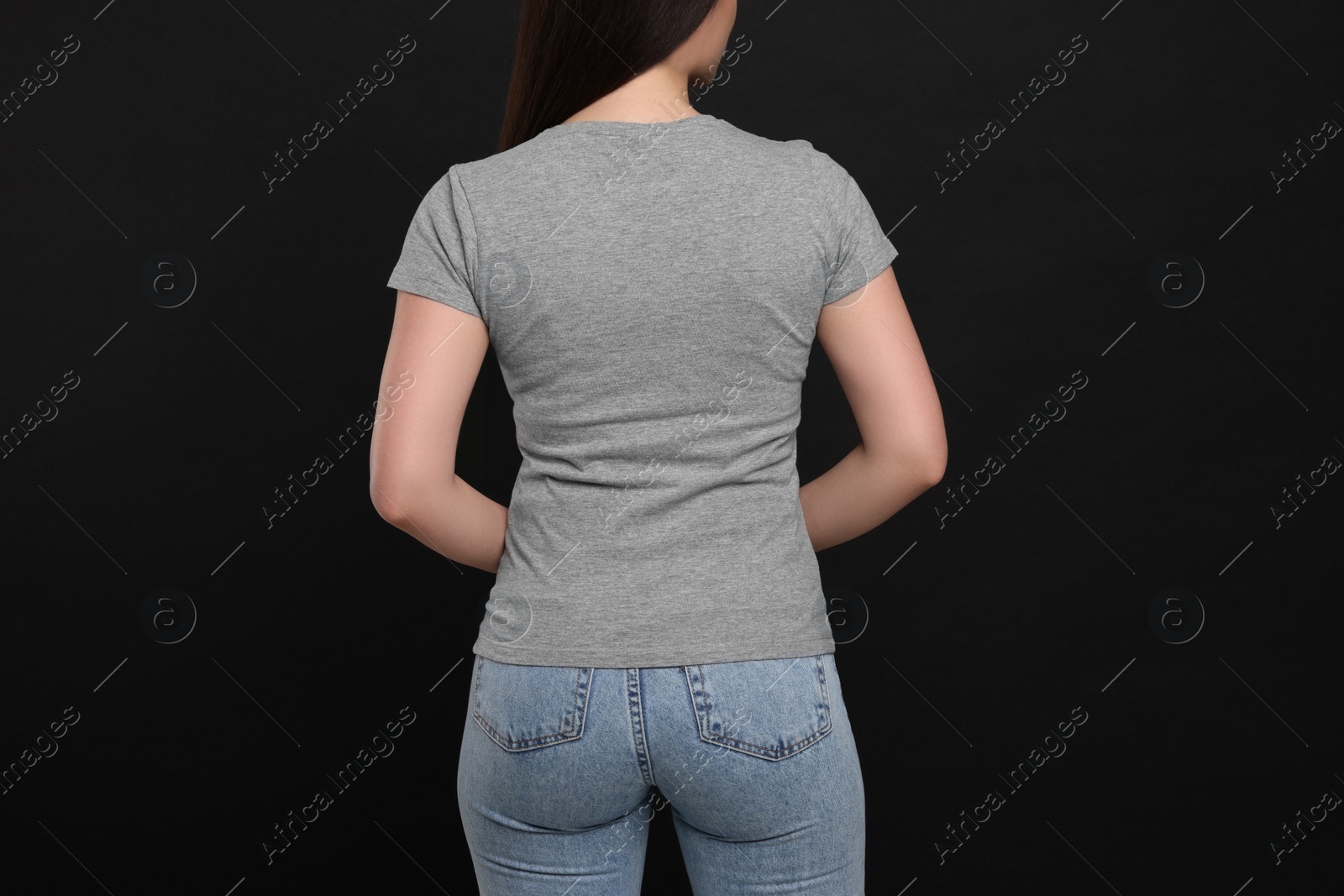 Photo of Woman wearing grey t-shirt on black background, back view