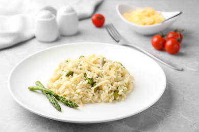 Photo of Delicious risotto with asparagus on grey marble table