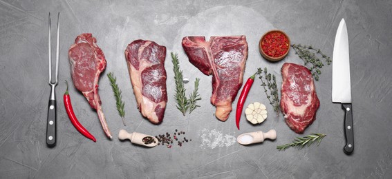 Photo of Fresh raw beef cuts, butcher tools and different spices on light grey textured table, flat lay