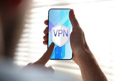Man using smartphone with switched on VPN indoors, closeup