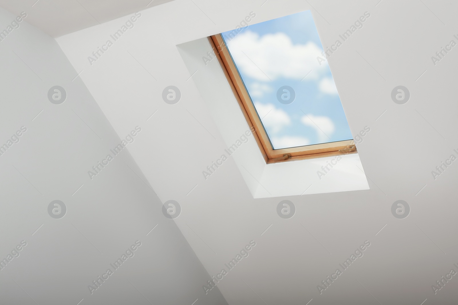 Photo of Skylight roof window and lamps on slanted ceiling in attic room, low angle view