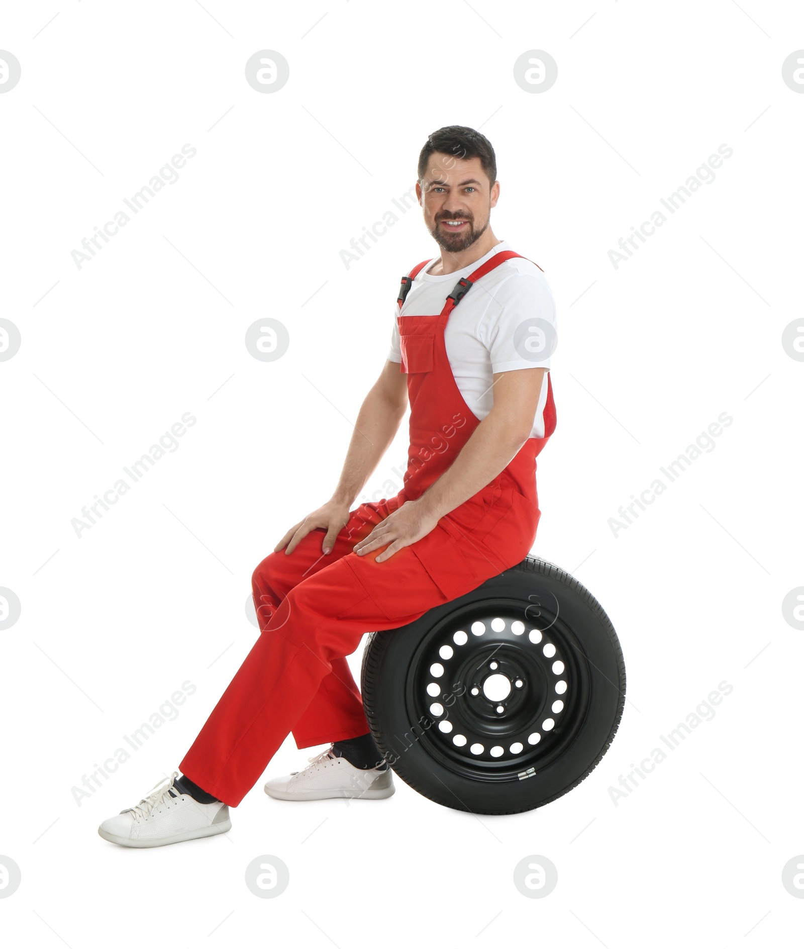 Photo of Full length portrait of professional auto mechanic with wheel on white background