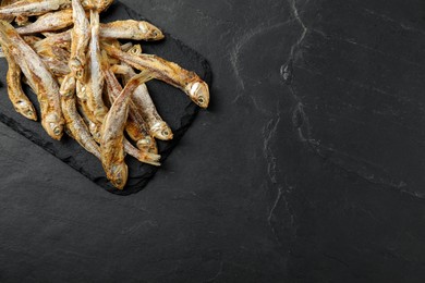 Delicious dried anchovies on black table, top view. Space for text