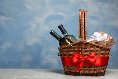 Photo of Gift basket with bottles of wine on color background. Space for text