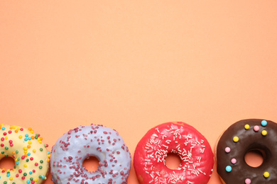 Photo of Delicious glazed donuts on orange background, flat lay. Space for text