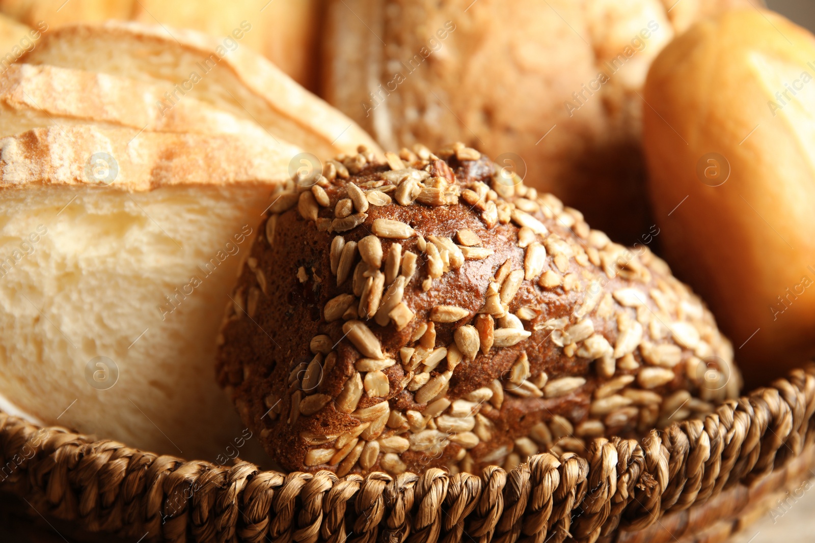 Photo of Wicker basket with different kinds of bread, closeup