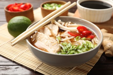 Delicious ramen with meat and ingredients on wooden table, closeup. Noodle soup