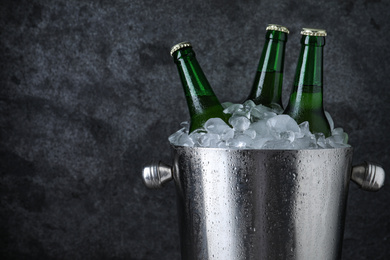 Metal bucket with beer and ice cubes on grey background, closeup. Space for text