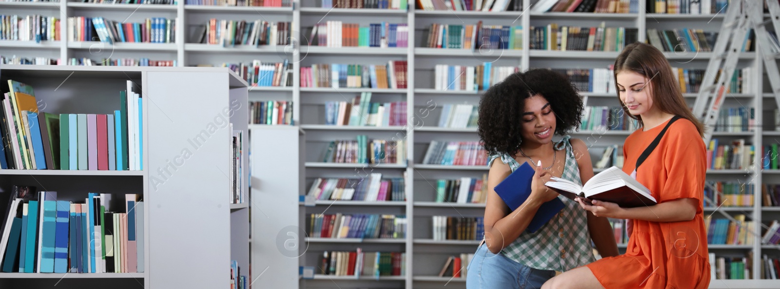 Image of Young students with books in modern library, space for text. Banner design