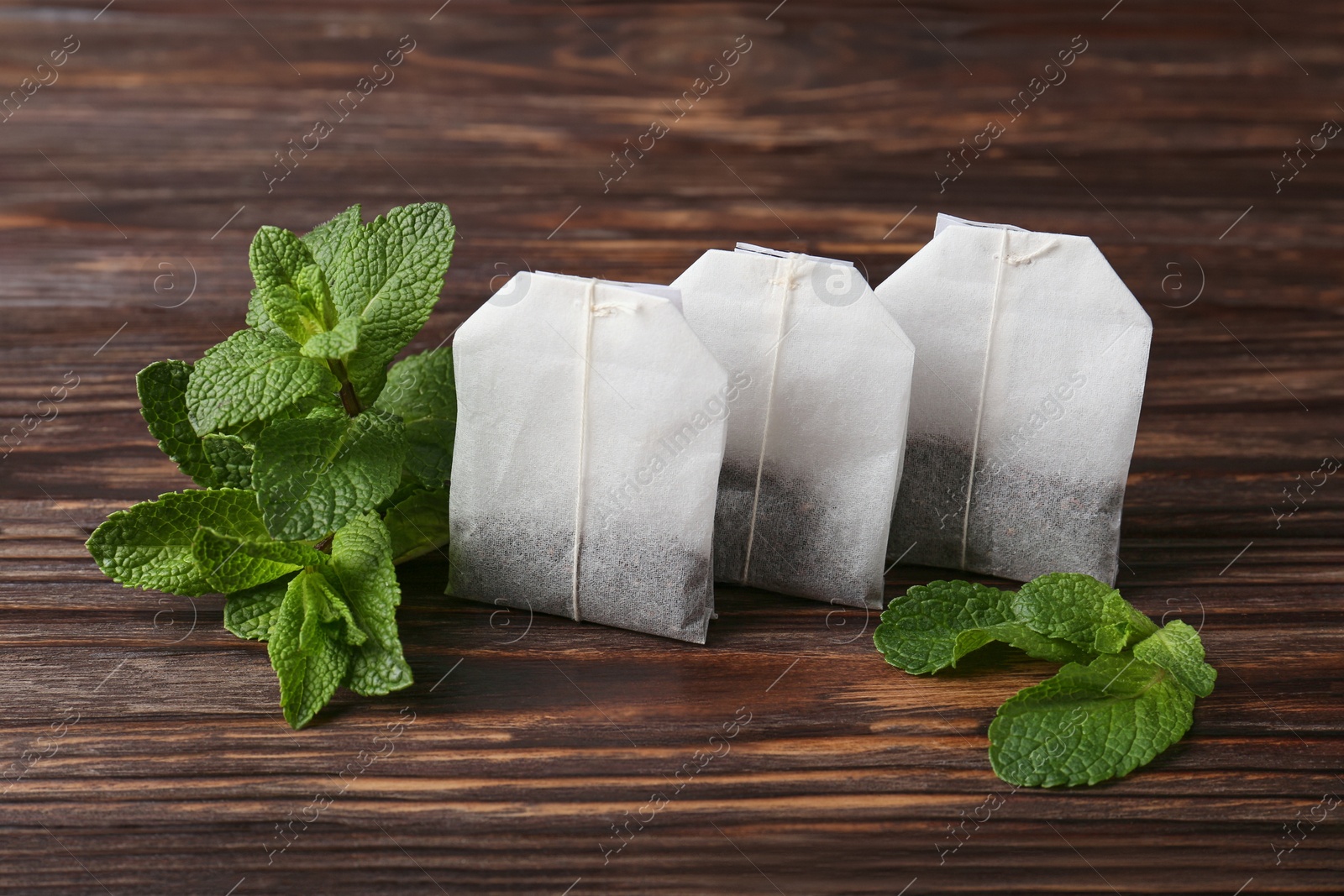 Photo of Tea bags and mint on wooden table, closeup
