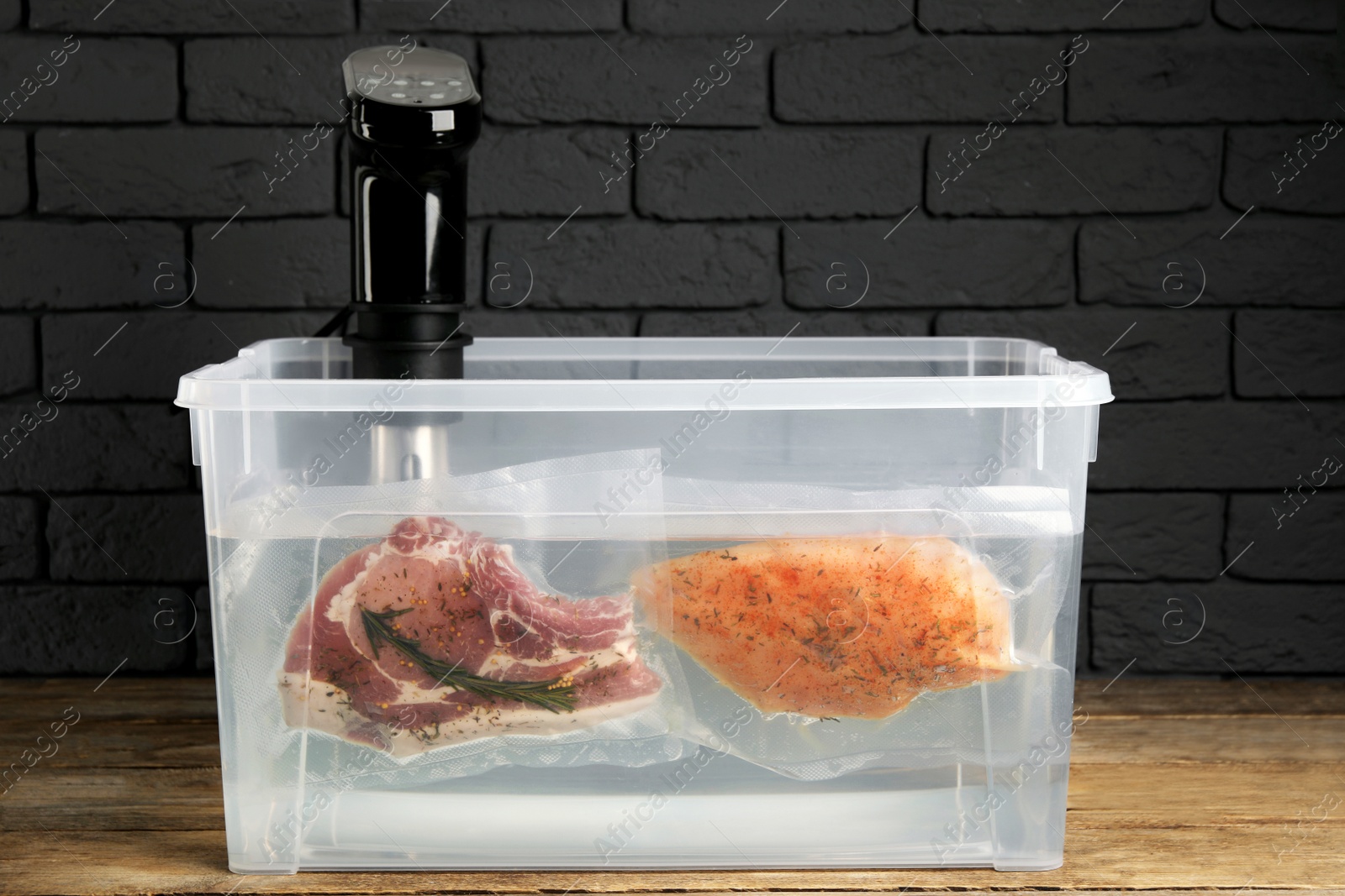 Photo of Thermal immersion circulator and vacuum packed meat in box on wooden table. Sous vide cooking