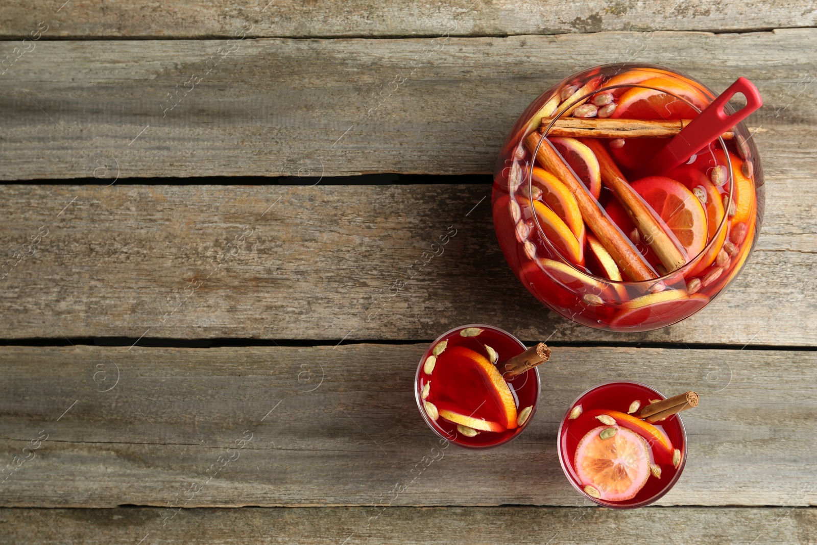 Photo of Glasses and bowl with aromatic punch drink on wooden table, flat lay. Space for text