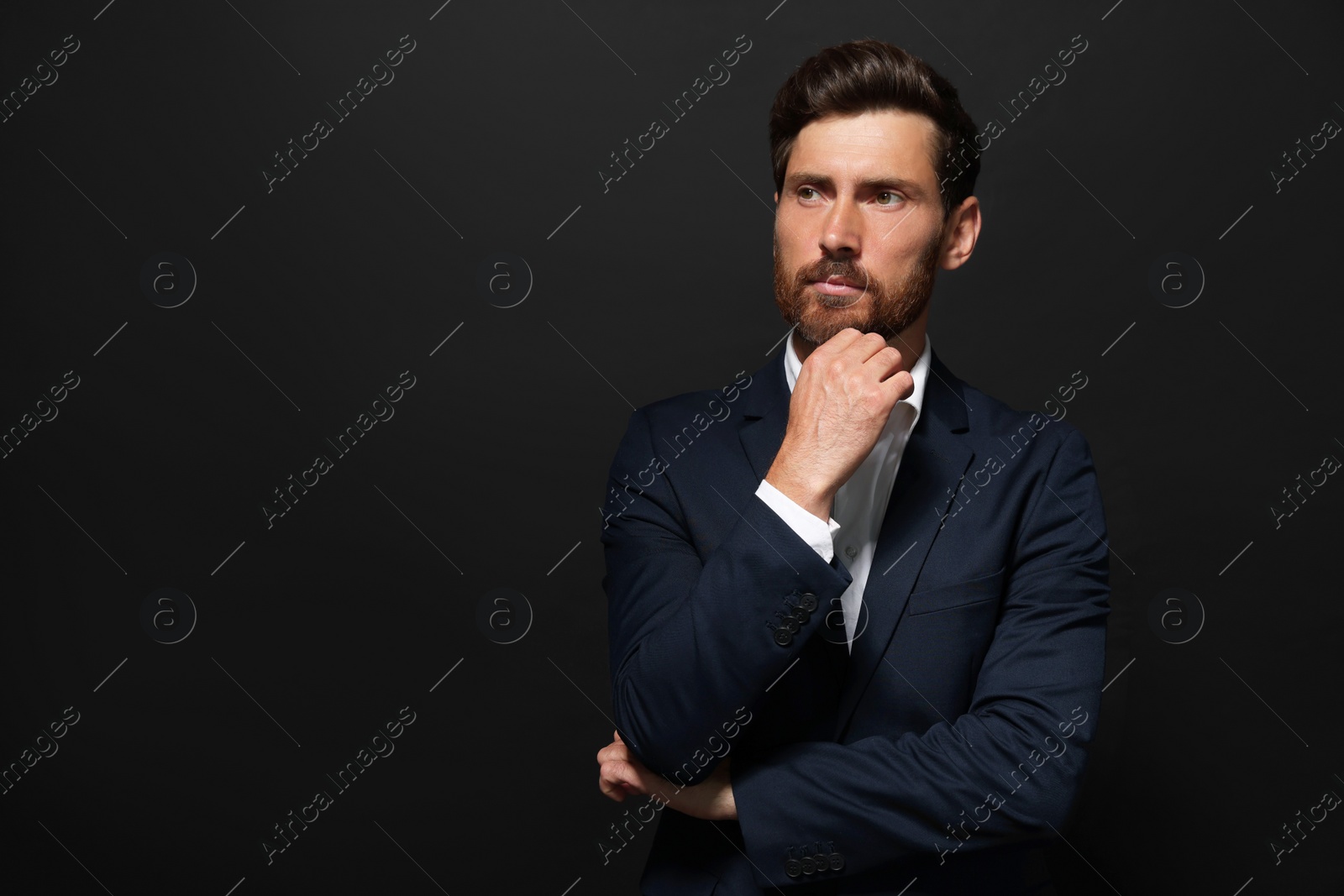 Photo of Portrait of handsome bearded man looking away on black background. Space for text