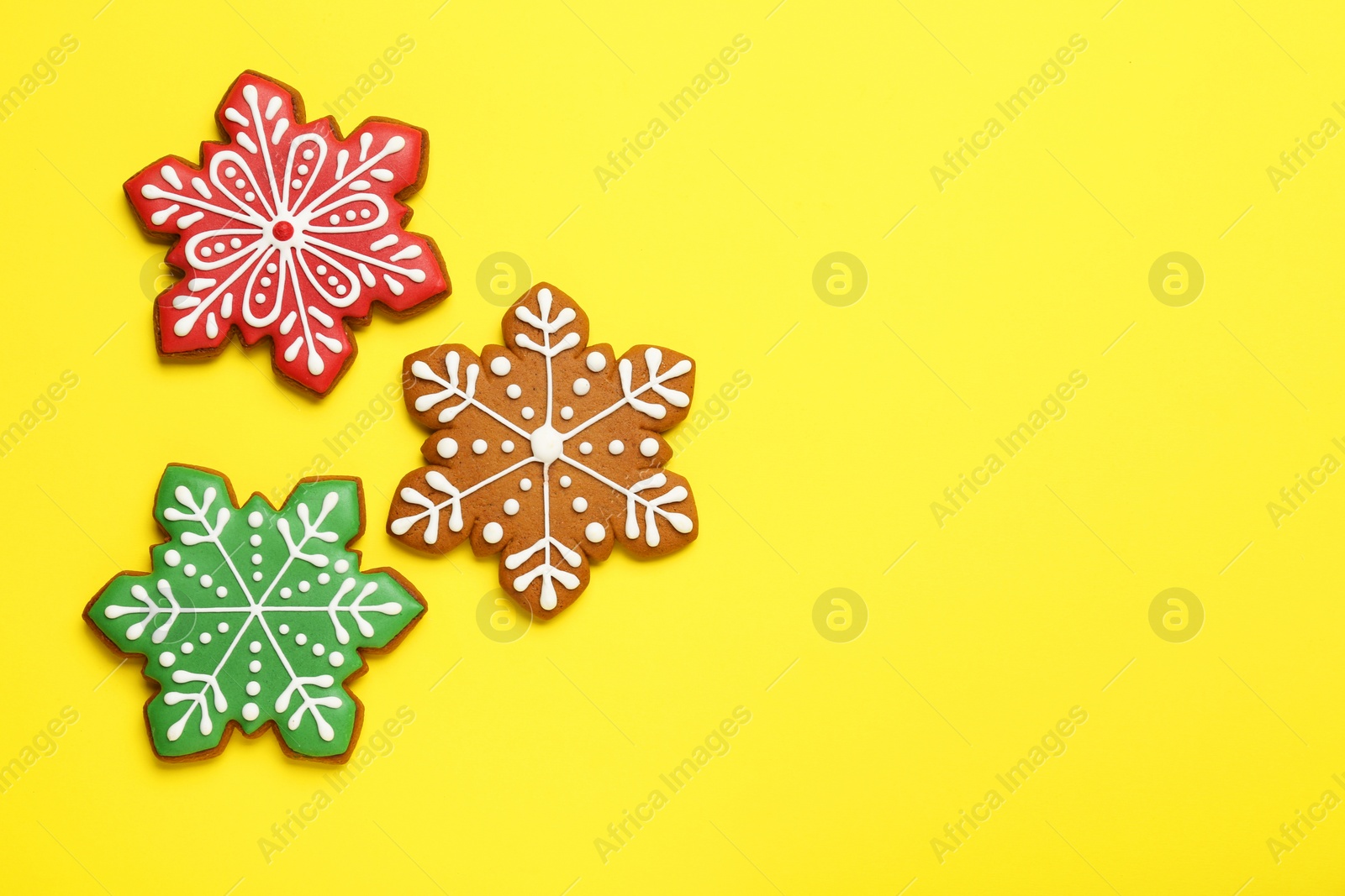 Photo of Tasty Christmas cookies in shape of snowflakes on yellow background, flat lay. Space for text