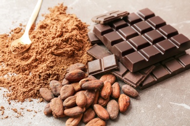 Photo of Delicious chocolate, cocoa powder and beans on table