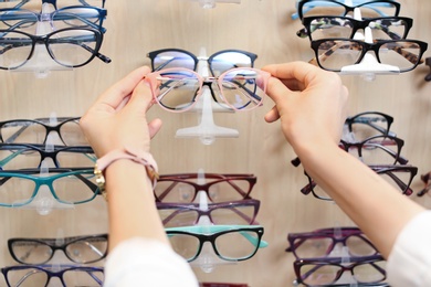 Photo of Female ophthalmologist taking glasses from showcase in optical store