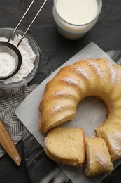 Delicious freshly baked sponge cake served on black table, flat lay