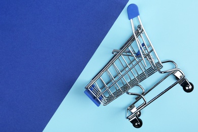 Empty shopping trolley on color background, top view. Space for text