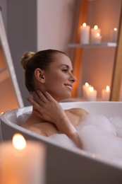 Beautiful woman taking bath in tub with foam indoors. Romantic atmosphere