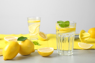 Glass with lemon water and fresh fruits on table