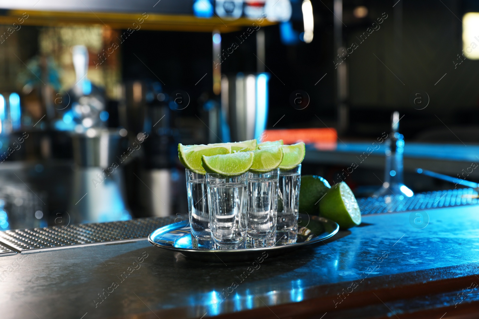 Photo of Mexican Tequila shots with lime slices on bar counter