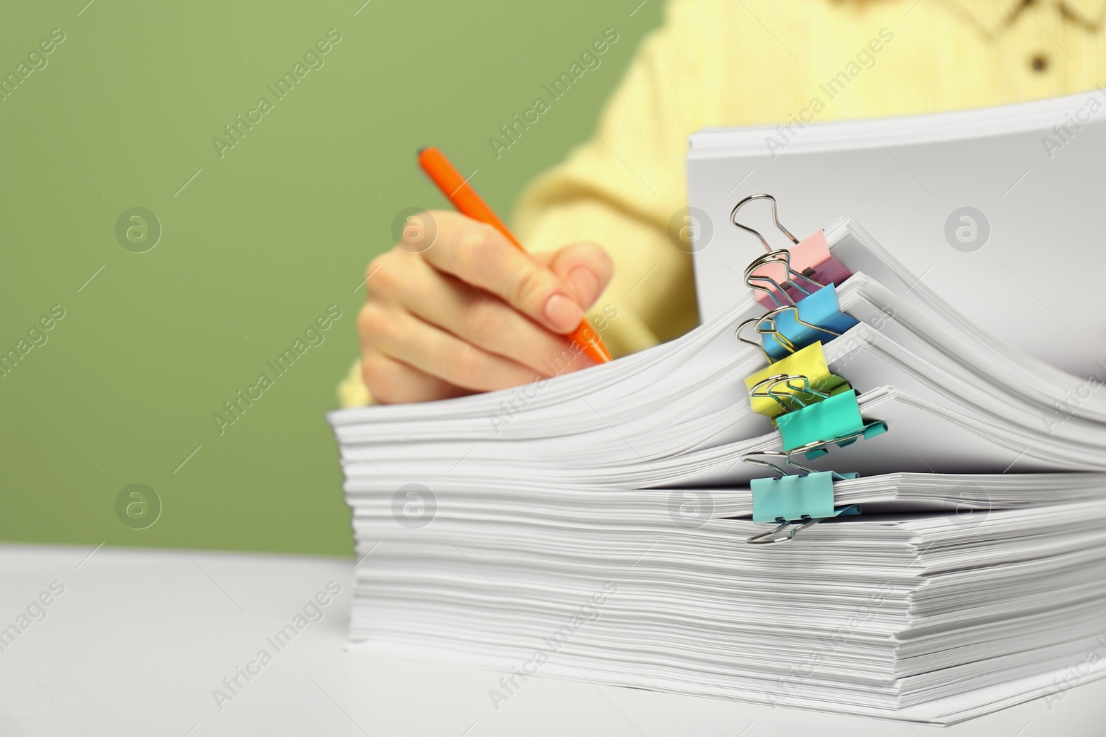 Photo of Woman signing documents at white table against green background, closeup