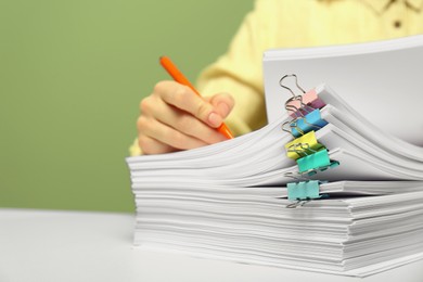 Woman signing documents at white table against green background, closeup