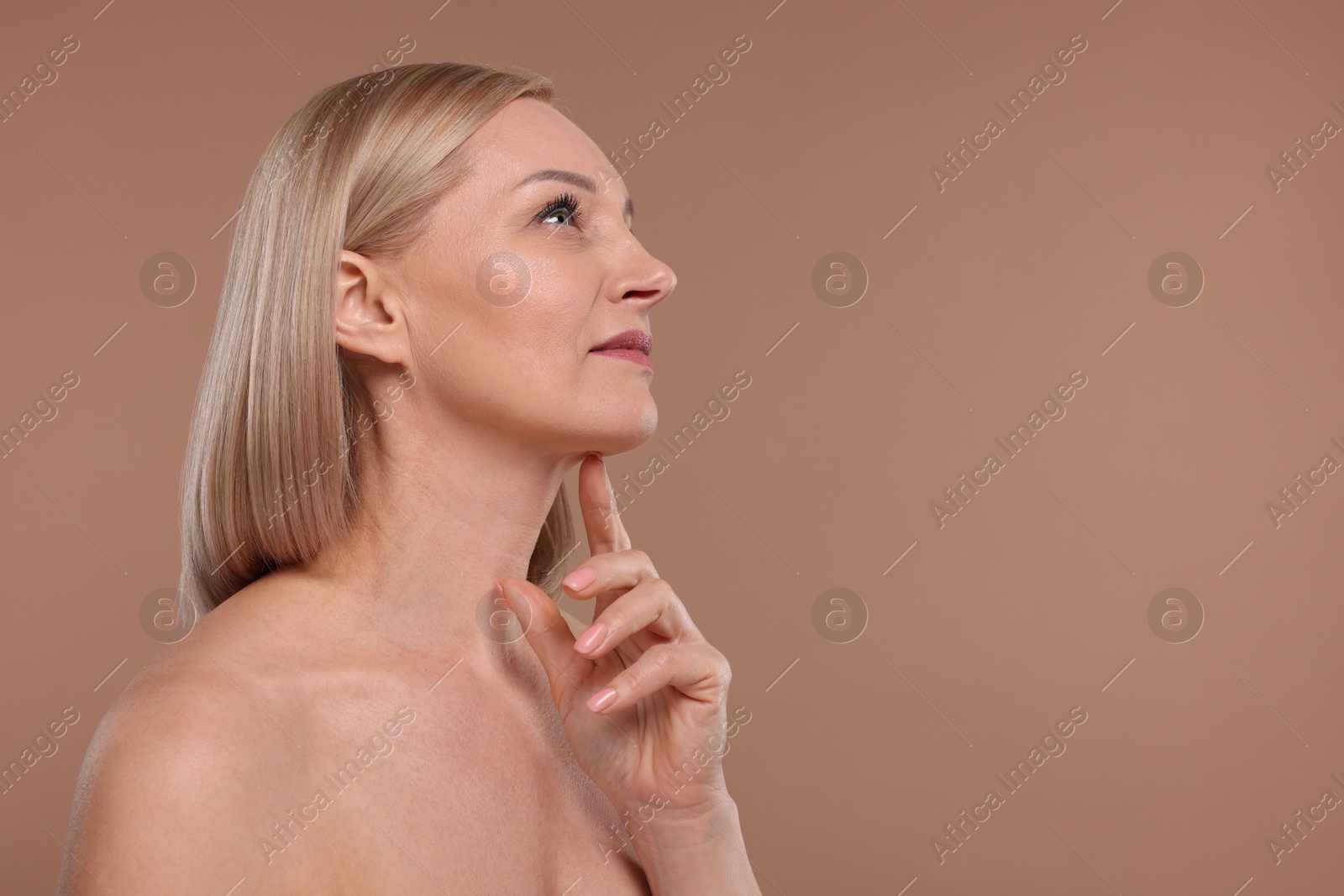 Photo of Beautiful woman touching her neck on beige background, space for text