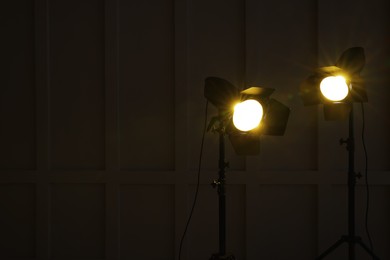 Photo of Bright yellow spotlights near wall in dark room, space for text