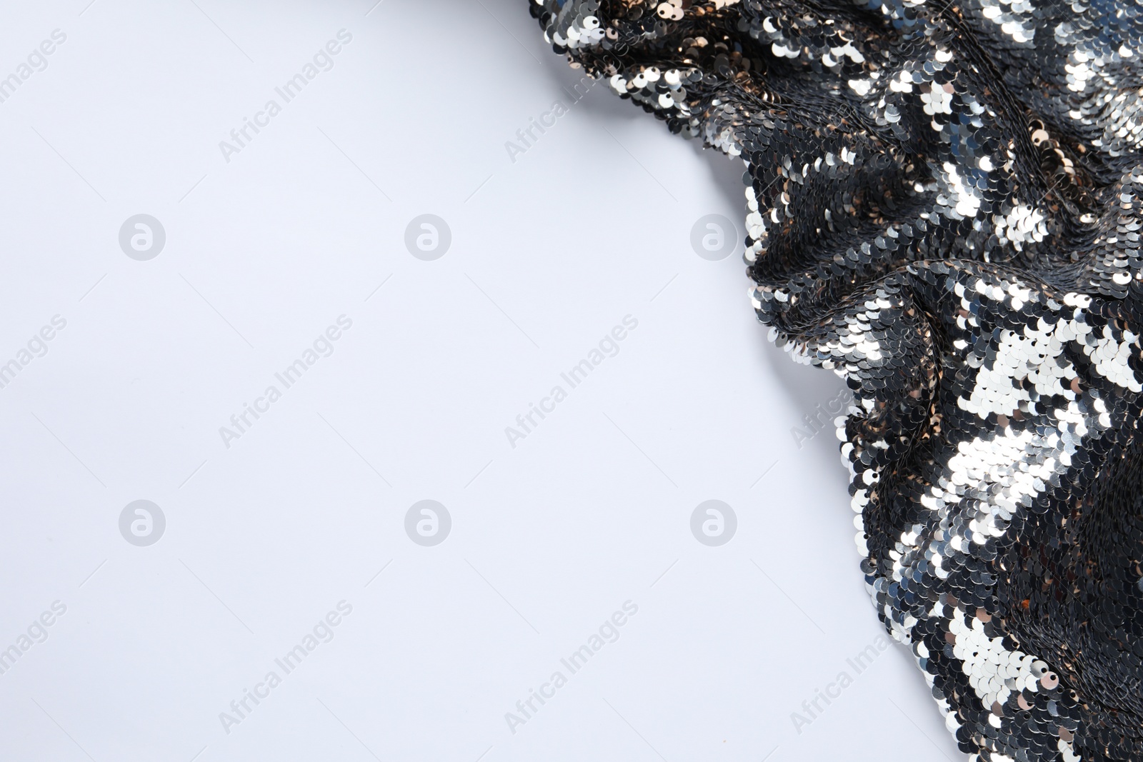 Photo of Beautiful bright sequin fabric on white background, above view. Space for text