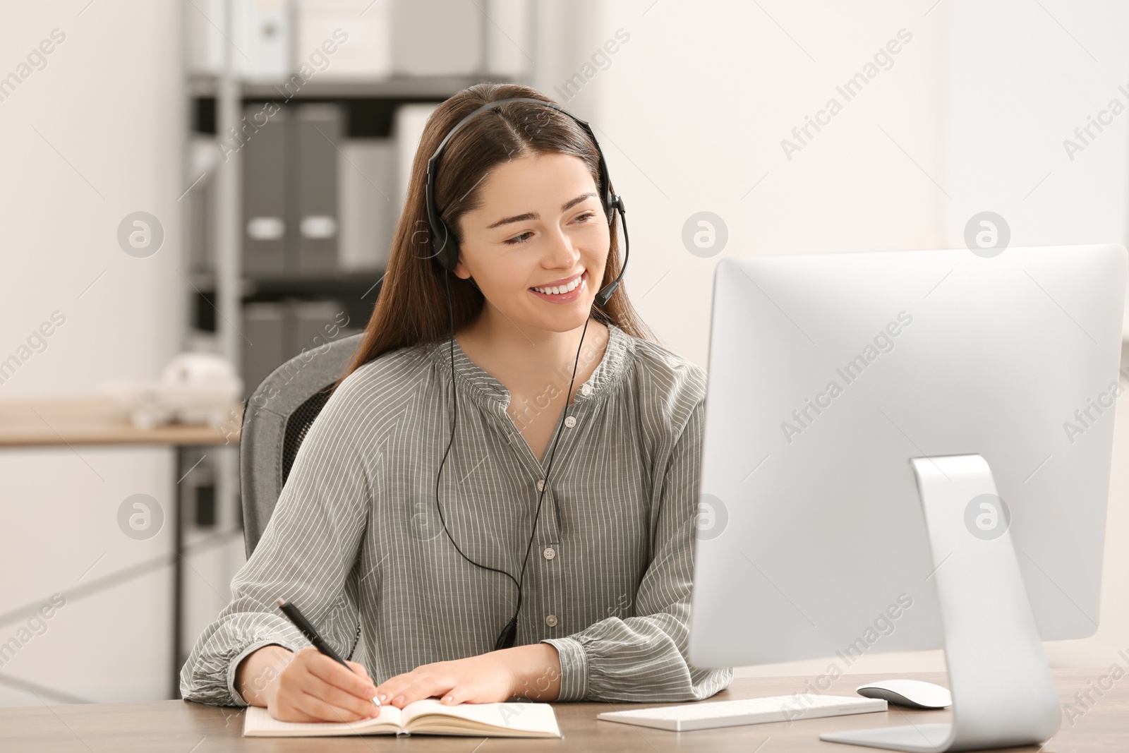 Photo of Hotline operator with headset working on computer in office