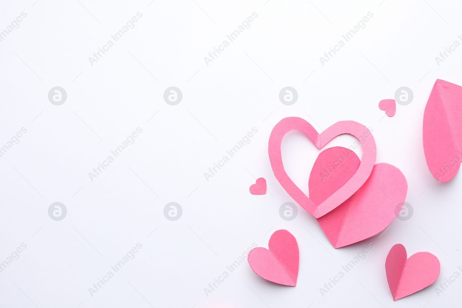 Photo of Pink paper hearts on white background, flat lay. Space for text