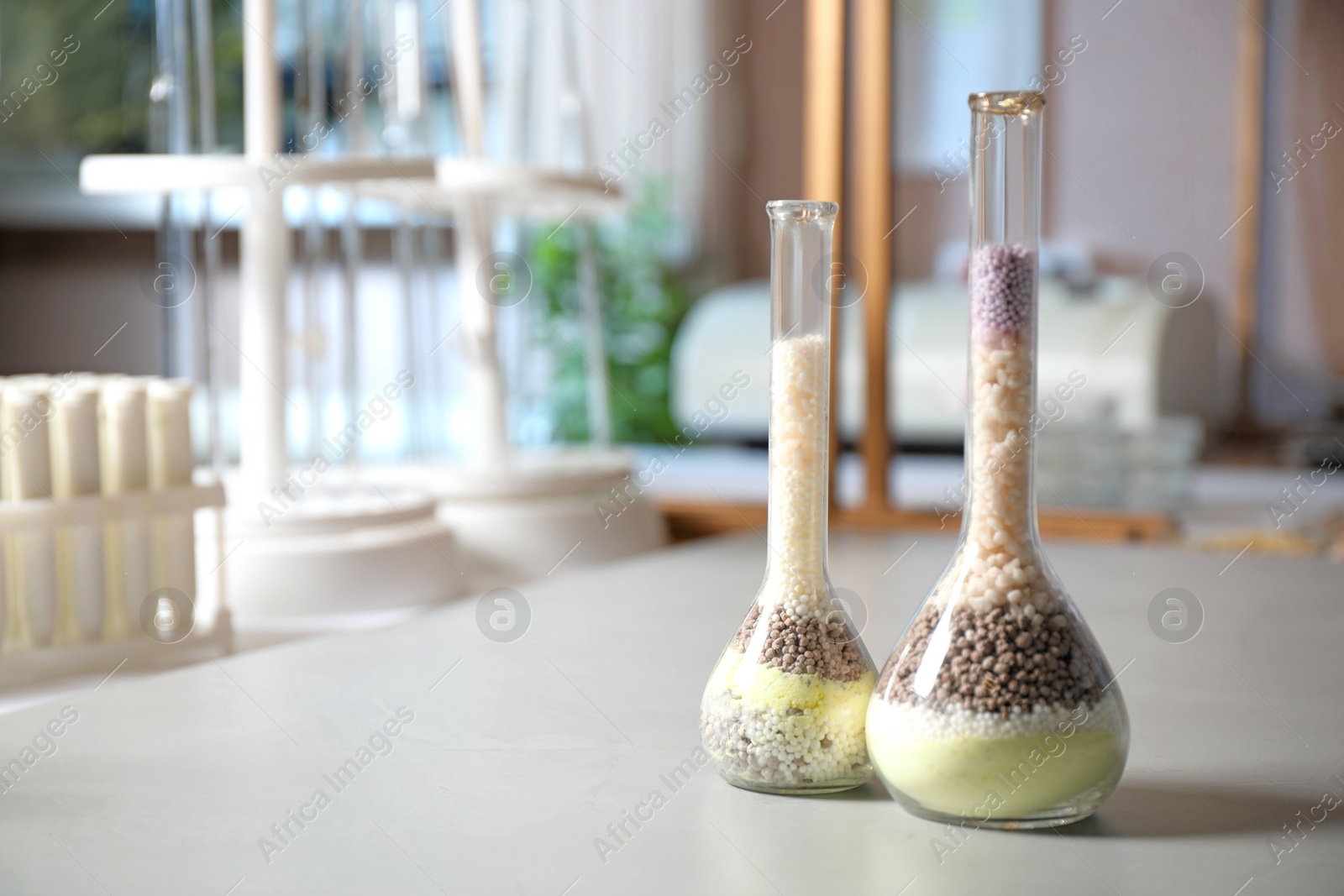 Photo of Glassware with mineral fertilizer on table in laboratory