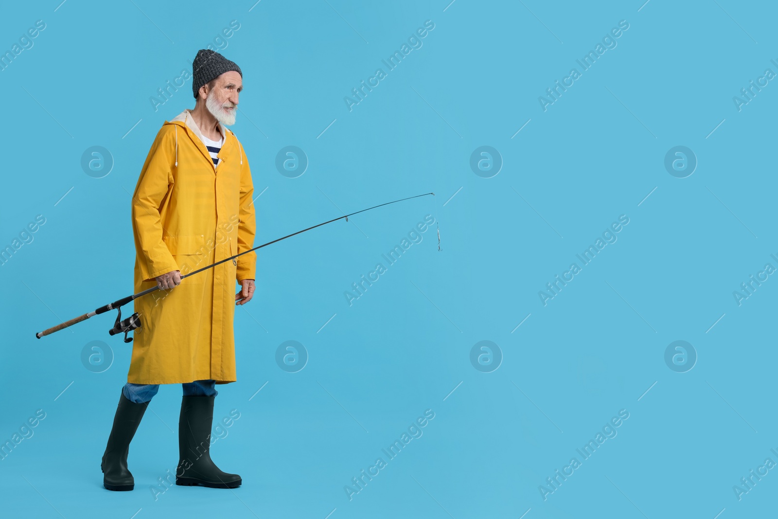 Photo of Fisherman with fishing rod on light blue background, space for text