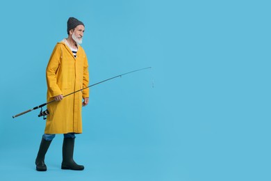 Fisherman with fishing rod on light blue background, space for text