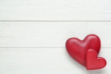 Photo of Red decorative hearts and space for text on white wooden table, flat lay. Valentine's Day