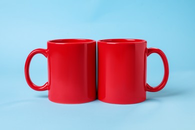 Photo of Two red ceramic mugs on light blue background