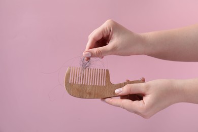 Photo of Woman taking her lost hair from comb on pink background, closeup. Space for text