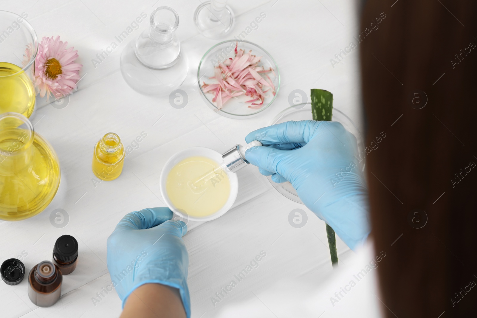 Photo of Scientist developing cosmetic oil at white table, above view