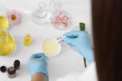 Photo of Scientist developing cosmetic oil at white table, above view