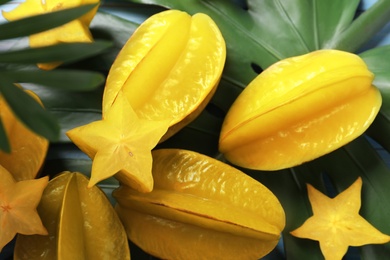 Delicious carambola fruits and green leaf on table