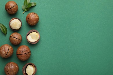 Photo of Tasty Macadamia nuts and leaves on green background, flat lay. Space for text