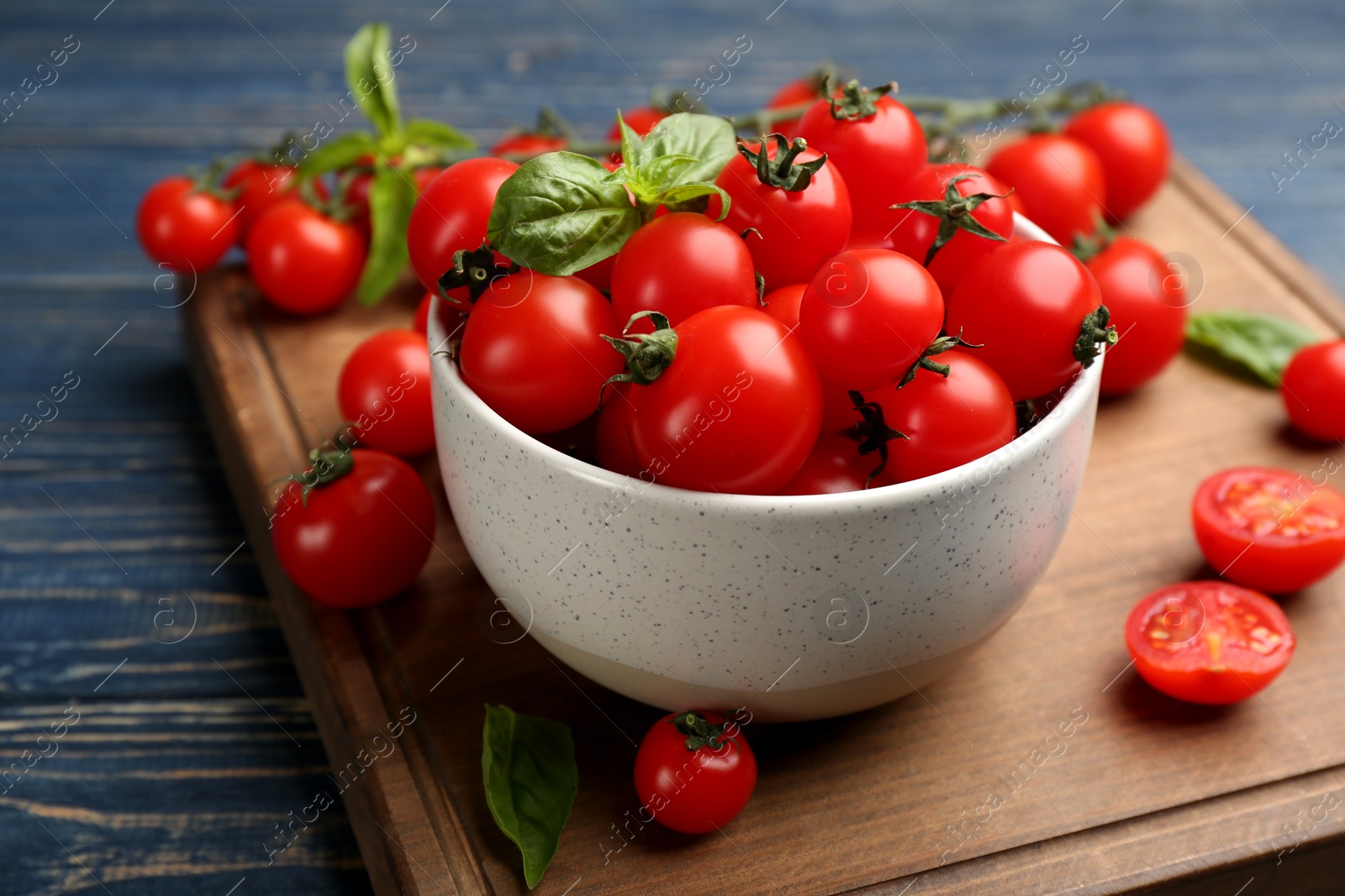 Photo of Fresh ripe cherry tomatoes and basil on blue wooden table, closeup