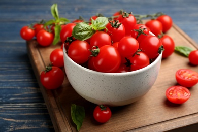 Fresh ripe cherry tomatoes and basil on blue wooden table, closeup