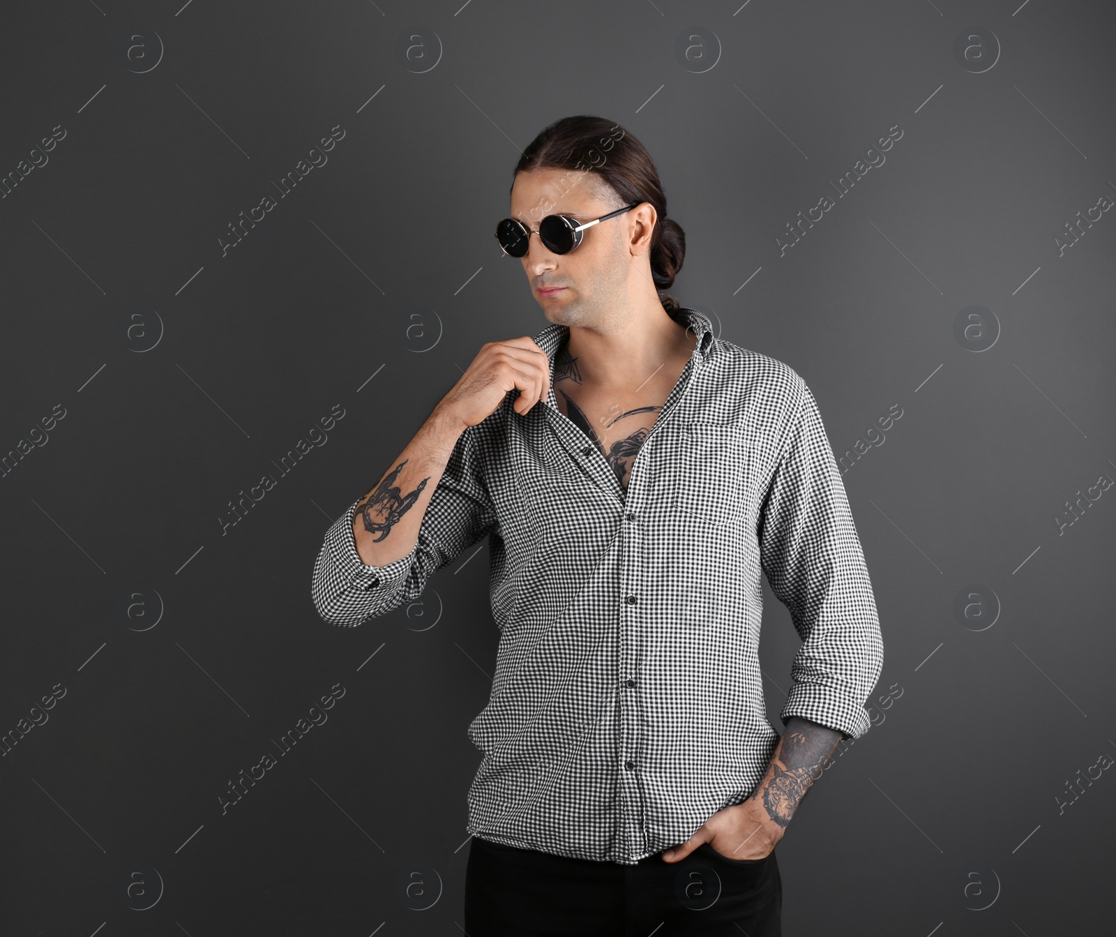 Photo of Young man with stylish tattoos on grey background. Space for text