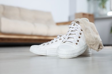 Photo of Sneakers with dirty socks on white wooden floor indoors